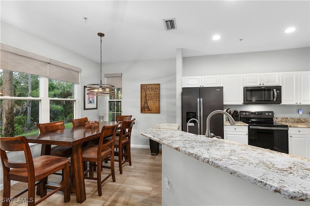 kitchen featuring black appliances, white cabinets, hanging light fixtures, light stone countertops, and light wood-type flooring