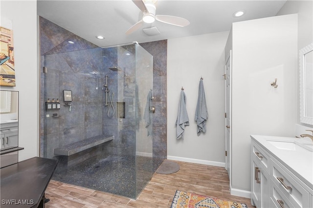 bathroom featuring a tile shower, ceiling fan, vanity, and wood-type flooring