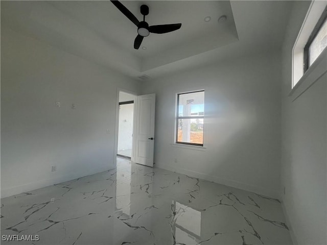 spare room featuring a tray ceiling and ceiling fan