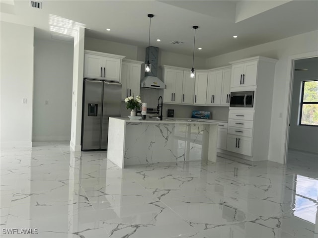 kitchen featuring wall chimney range hood, an island with sink, appliances with stainless steel finishes, and white cabinetry