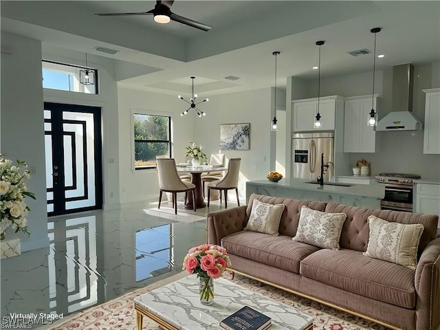 living room with marble finish floor, visible vents, and ceiling fan with notable chandelier