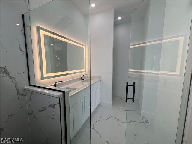 full bathroom with double vanity, marble finish floor, a marble finish shower, and a sink