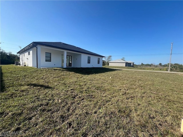 view of front of property with stucco siding, a front lawn, and central AC unit