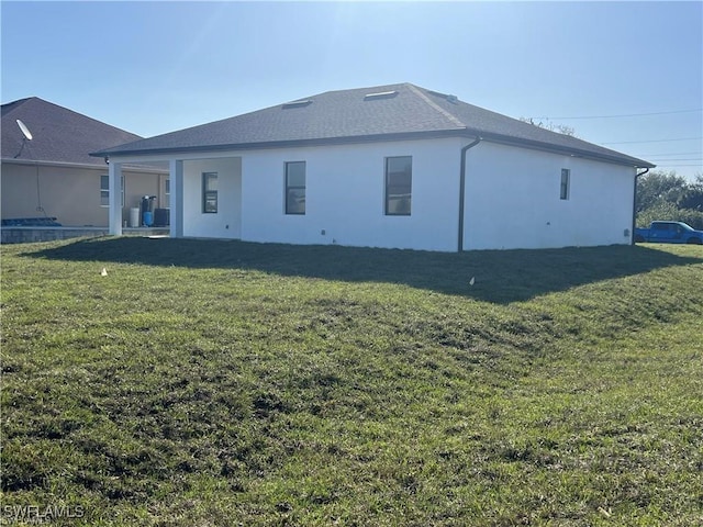 back of property with a yard and stucco siding