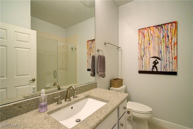 bathroom with vanity, a shower stall, toilet, and baseboards