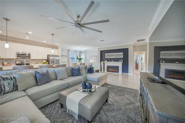 living room with ceiling fan and ornamental molding