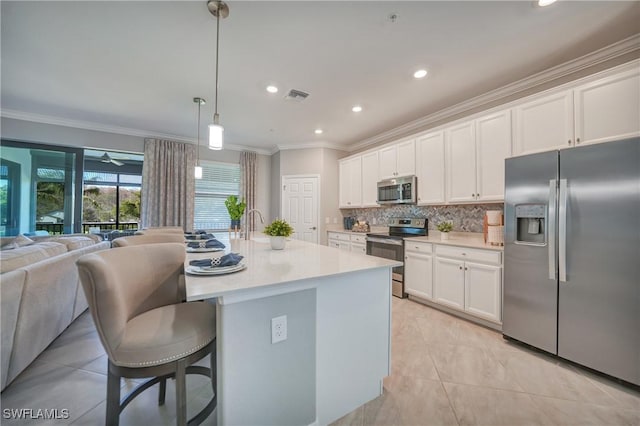 kitchen with tasteful backsplash, stainless steel appliances, pendant lighting, a center island with sink, and white cabinetry