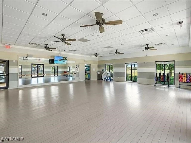 workout area with a paneled ceiling and light hardwood / wood-style floors