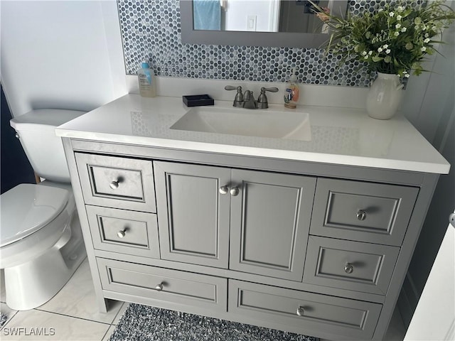 bathroom featuring tile patterned flooring, vanity, toilet, and tasteful backsplash