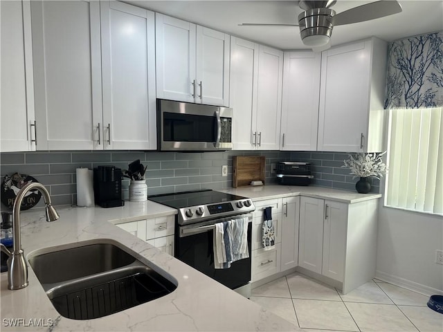 kitchen with light stone countertops, sink, white cabinets, and stainless steel appliances