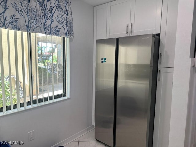 kitchen featuring stainless steel fridge, white cabinets, and light tile patterned floors