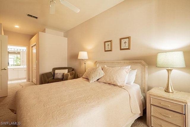 bedroom with ceiling fan, light colored carpet, and ensuite bath