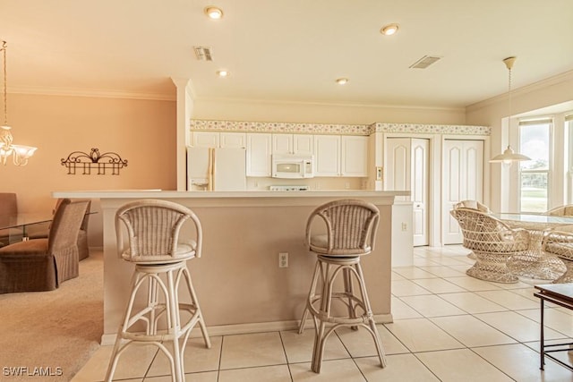 kitchen with a kitchen breakfast bar, hanging light fixtures, white appliances, and ornamental molding