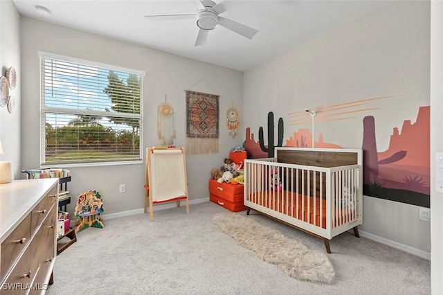 carpeted bedroom with a crib and ceiling fan