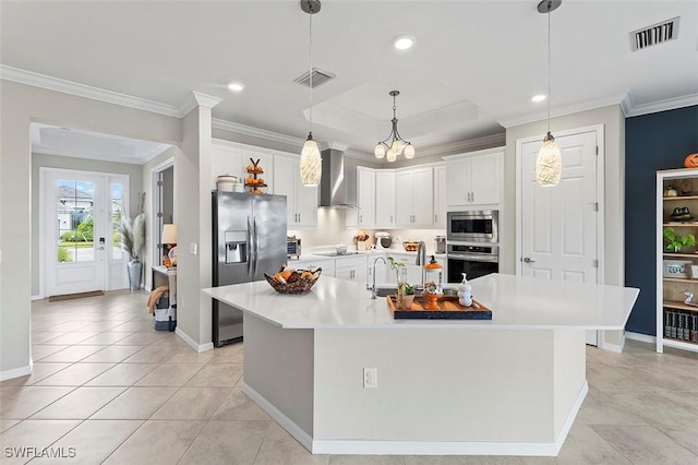 kitchen featuring white cabinets, stainless steel appliances, a kitchen island with sink, and wall chimney range hood