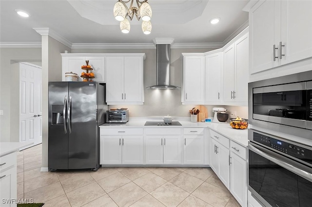 kitchen featuring appliances with stainless steel finishes, wall chimney exhaust hood, crown molding, an inviting chandelier, and white cabinets