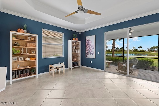 spare room featuring ornamental molding, a raised ceiling, ceiling fan, light tile patterned floors, and a water view