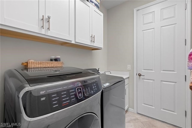 laundry room featuring cabinets, light tile patterned flooring, and washing machine and clothes dryer