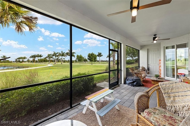 unfurnished sunroom featuring a water view, plenty of natural light, and ceiling fan