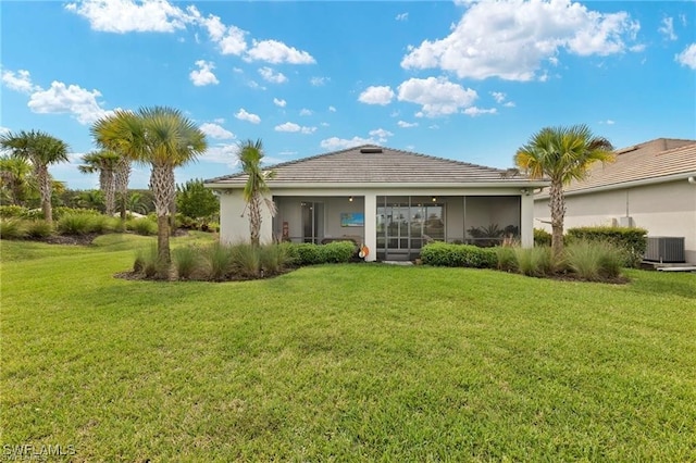 rear view of property featuring a sunroom, a yard, and central AC unit