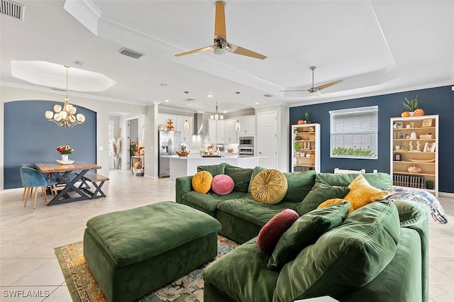 living room featuring light tile patterned floors, ceiling fan with notable chandelier, a raised ceiling, and crown molding