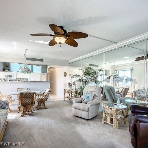 carpeted living room featuring a textured ceiling, ceiling fan, and ornamental molding