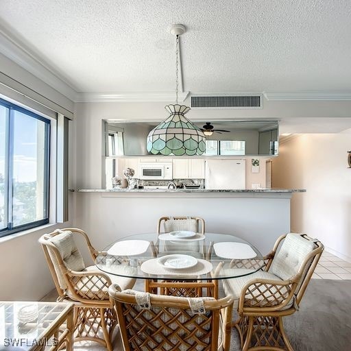 dining area featuring light tile patterned floors, a textured ceiling, ceiling fan, and crown molding