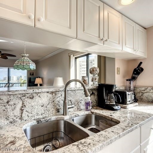 kitchen featuring white cabinetry, sink, ceiling fan, and light stone countertops