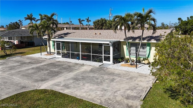 rear view of property with a lawn, a patio area, and a sunroom