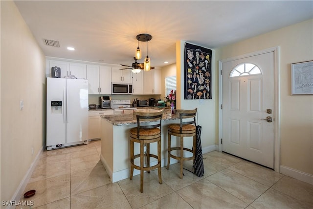 kitchen with pendant lighting, white appliances, dark stone counters, white cabinets, and kitchen peninsula