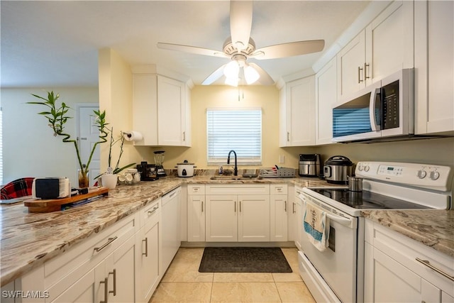 kitchen featuring white appliances, white cabinets, sink, ceiling fan, and light stone countertops