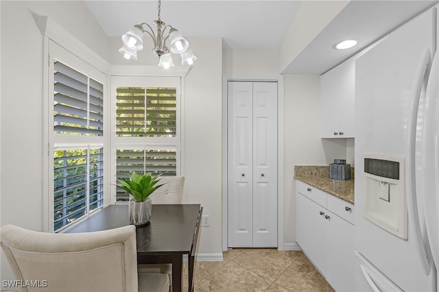 kitchen with white refrigerator with ice dispenser, white cabinets, decorative light fixtures, and a notable chandelier