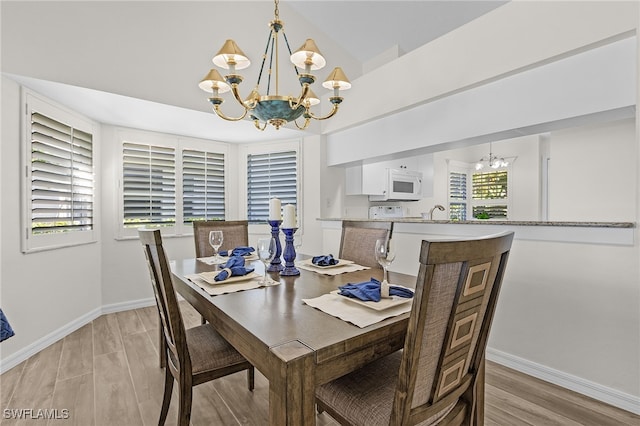 dining space with light hardwood / wood-style flooring, plenty of natural light, and an inviting chandelier