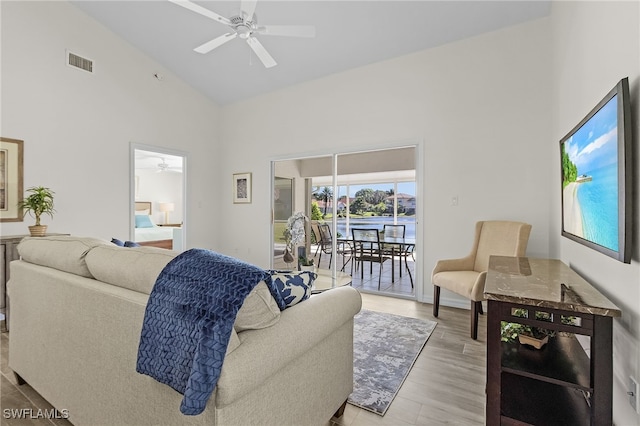 living room featuring ceiling fan, high vaulted ceiling, and light hardwood / wood-style flooring