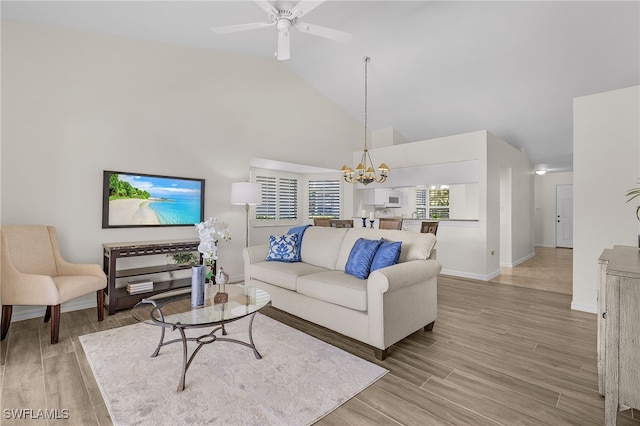 living room with ceiling fan with notable chandelier, light hardwood / wood-style floors, and high vaulted ceiling