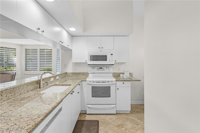 kitchen with white appliances, sink, light tile patterned floors, light stone counters, and white cabinetry