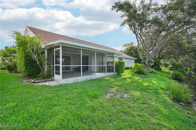 rear view of house with a sunroom and a yard