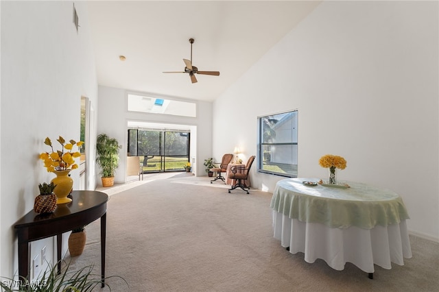 living area featuring ceiling fan, light colored carpet, and high vaulted ceiling