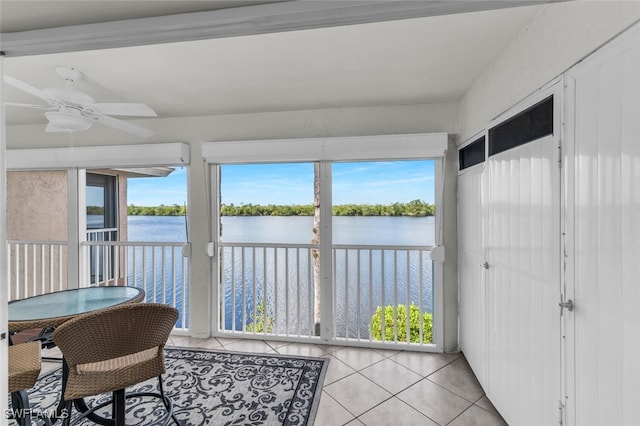 sunroom with a water view and ceiling fan