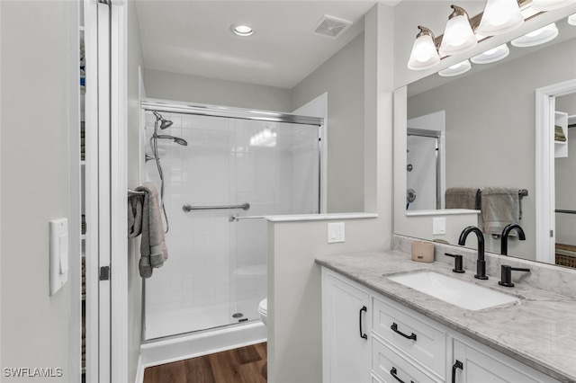 bathroom with wood-type flooring, vanity, toilet, and walk in shower