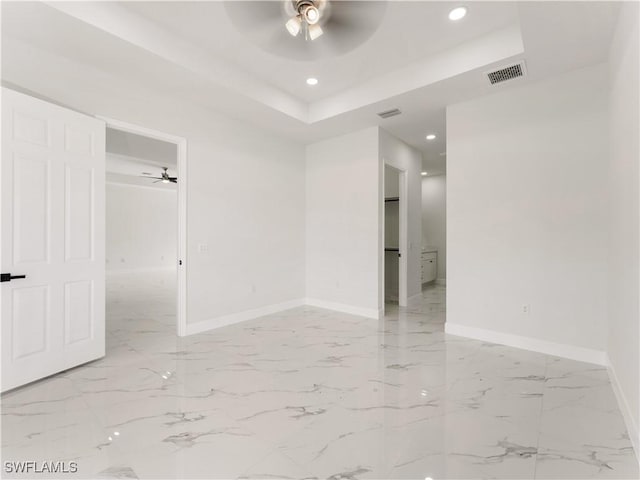 unfurnished room with ceiling fan and a raised ceiling