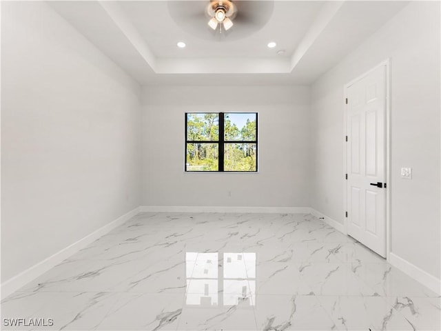 empty room with a raised ceiling and ceiling fan