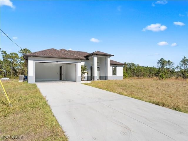 view of front of home featuring cooling unit, a garage, and a front yard