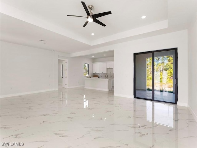 unfurnished room with a tray ceiling, ceiling fan, and sink