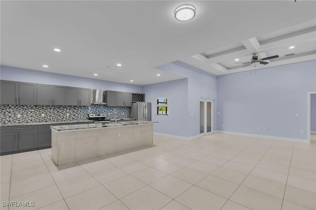 kitchen with backsplash, stainless steel appliances, extractor fan, beamed ceiling, and an island with sink