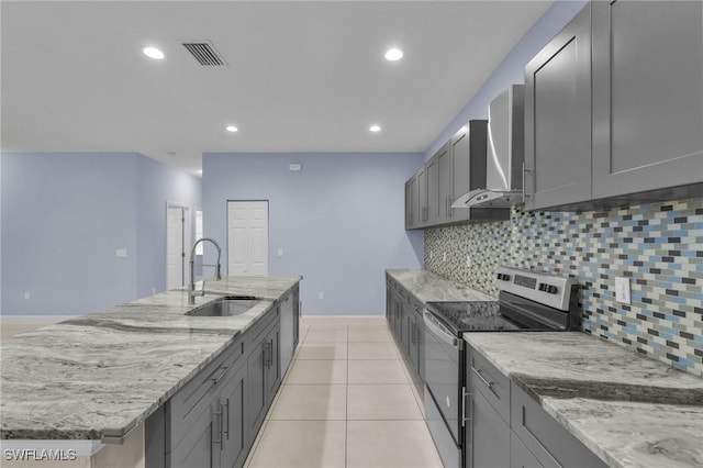 kitchen with tasteful backsplash, wall chimney range hood, sink, gray cabinets, and stainless steel electric range oven