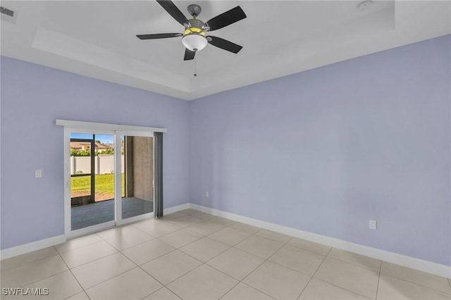 tiled empty room with a raised ceiling and ceiling fan