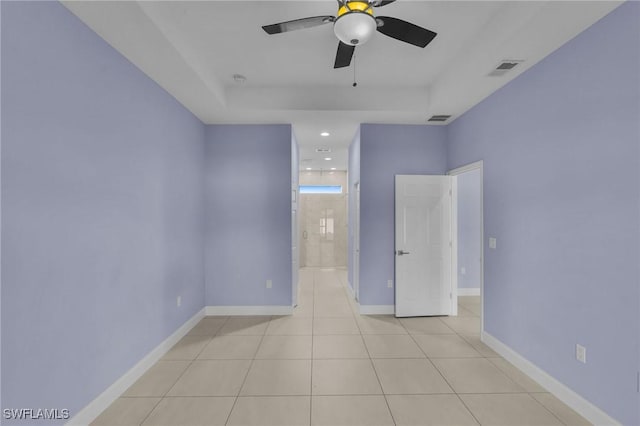 tiled empty room with a tray ceiling and ceiling fan