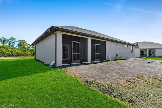 rear view of property featuring a lawn and a sunroom