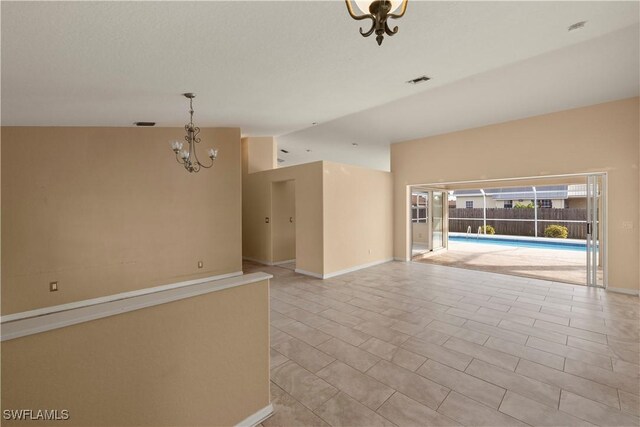 empty room with vaulted ceiling and a notable chandelier